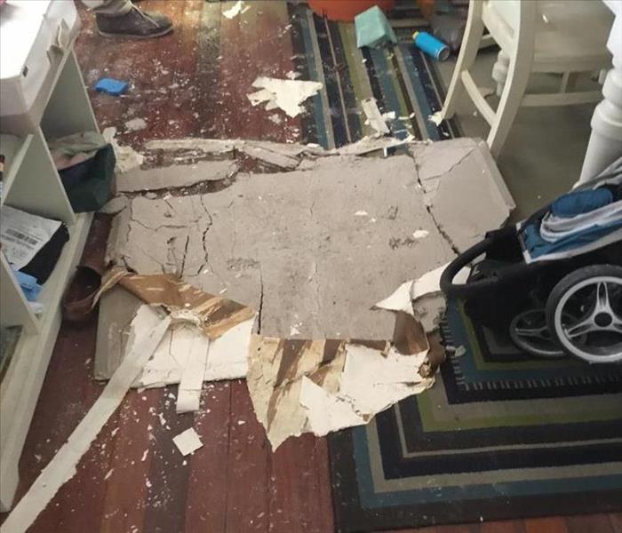 Large chunk of damaged sheet rock from ceiling lies on living room floor