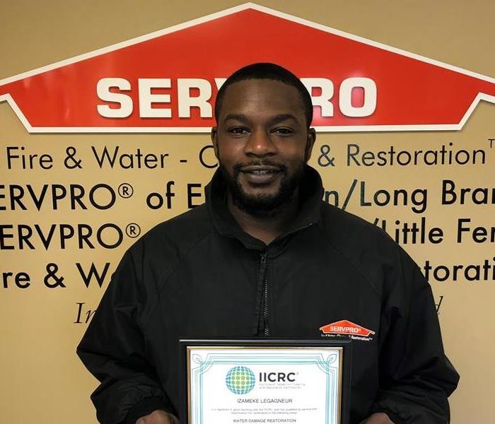 Team member, Meek, standing in from of SERVPRO logo with IICRC certification 